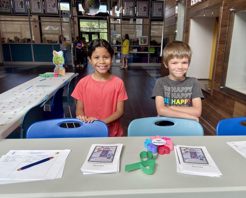 First-graders Amara Davis, left, and Liam Griffith welcome guests and pass out name tags.
